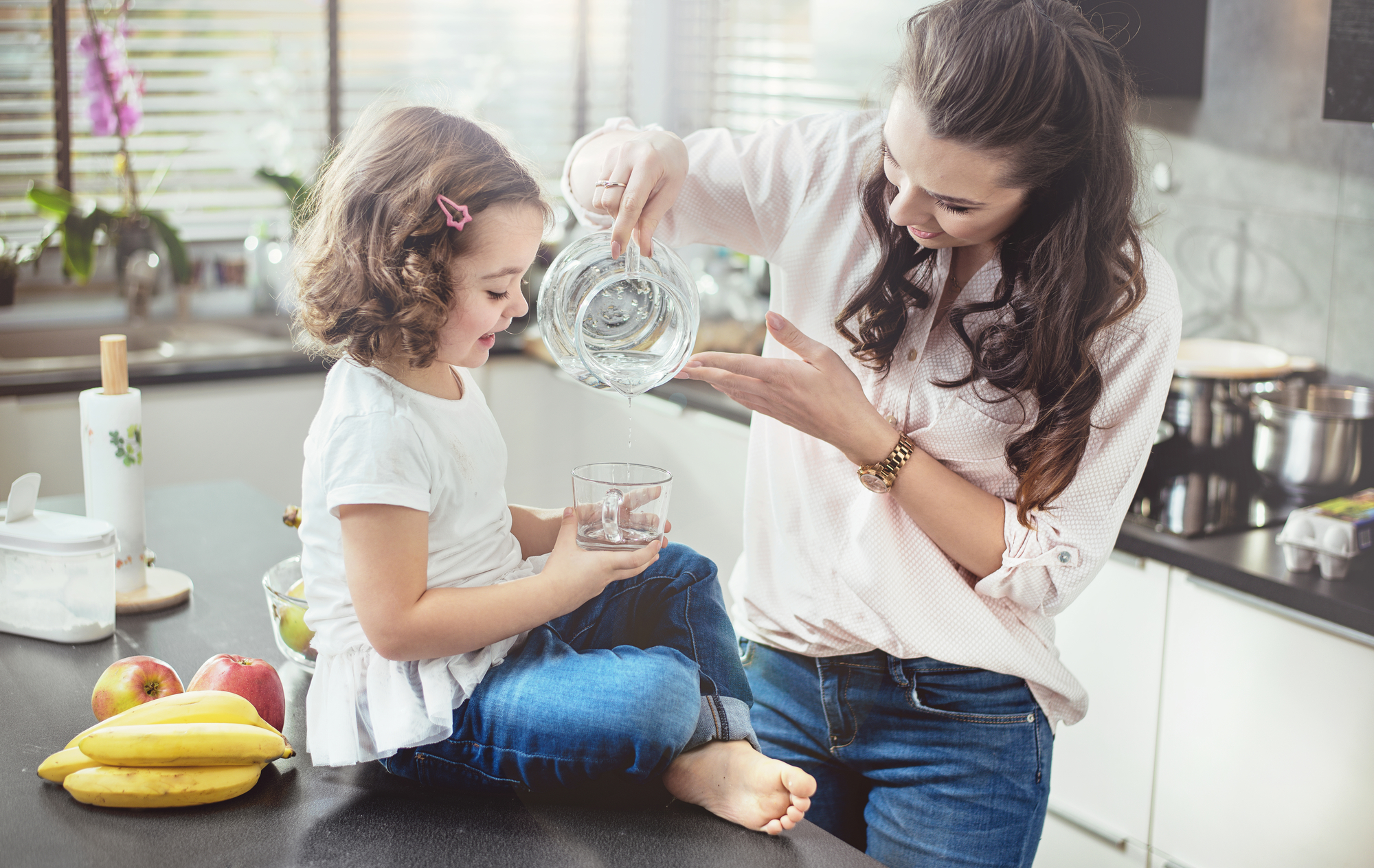 Woman filling a glass with water for her daughter